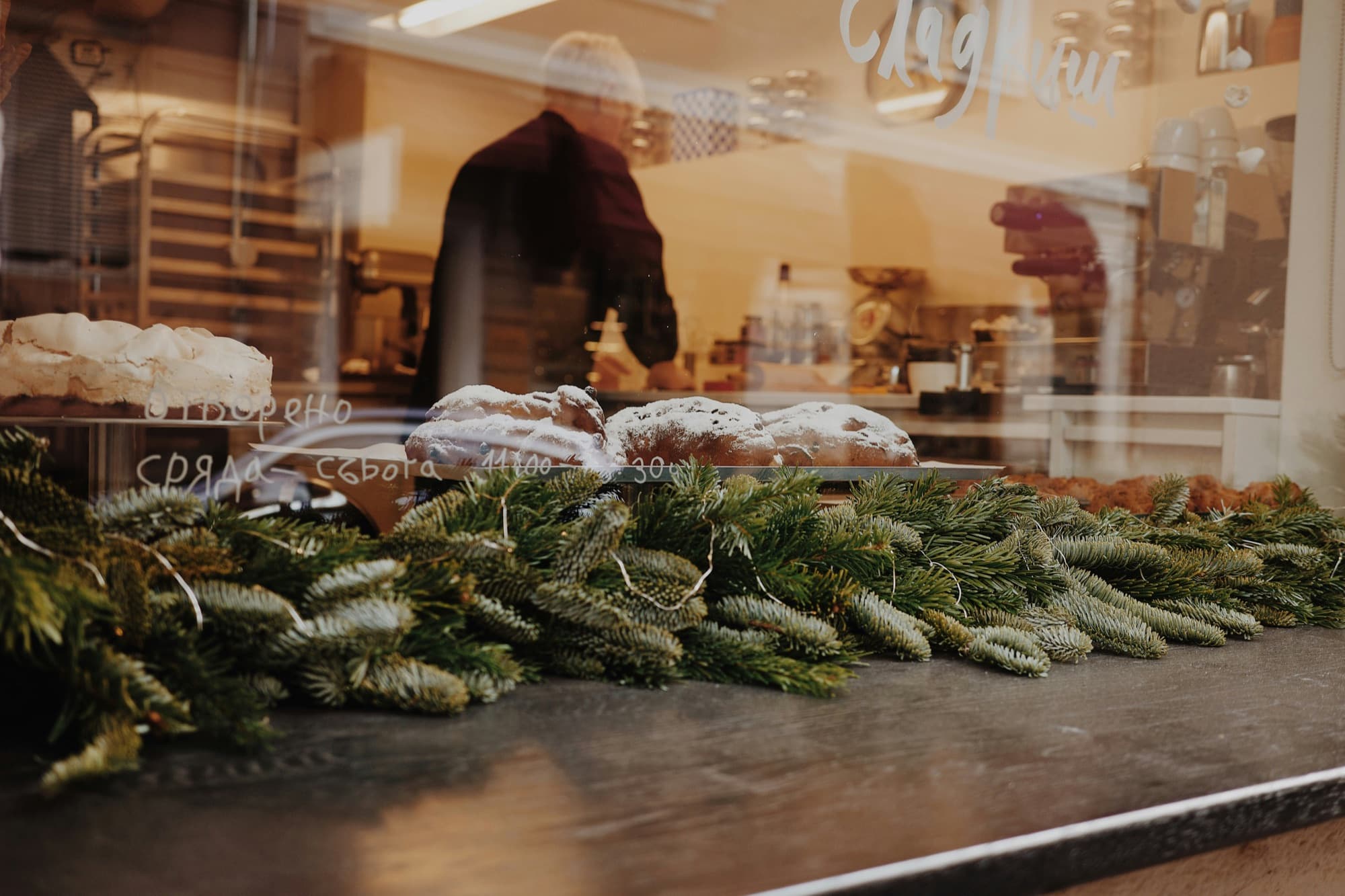 A shop window at Christmas, with stollen behind the glass and pine branches along the sill
