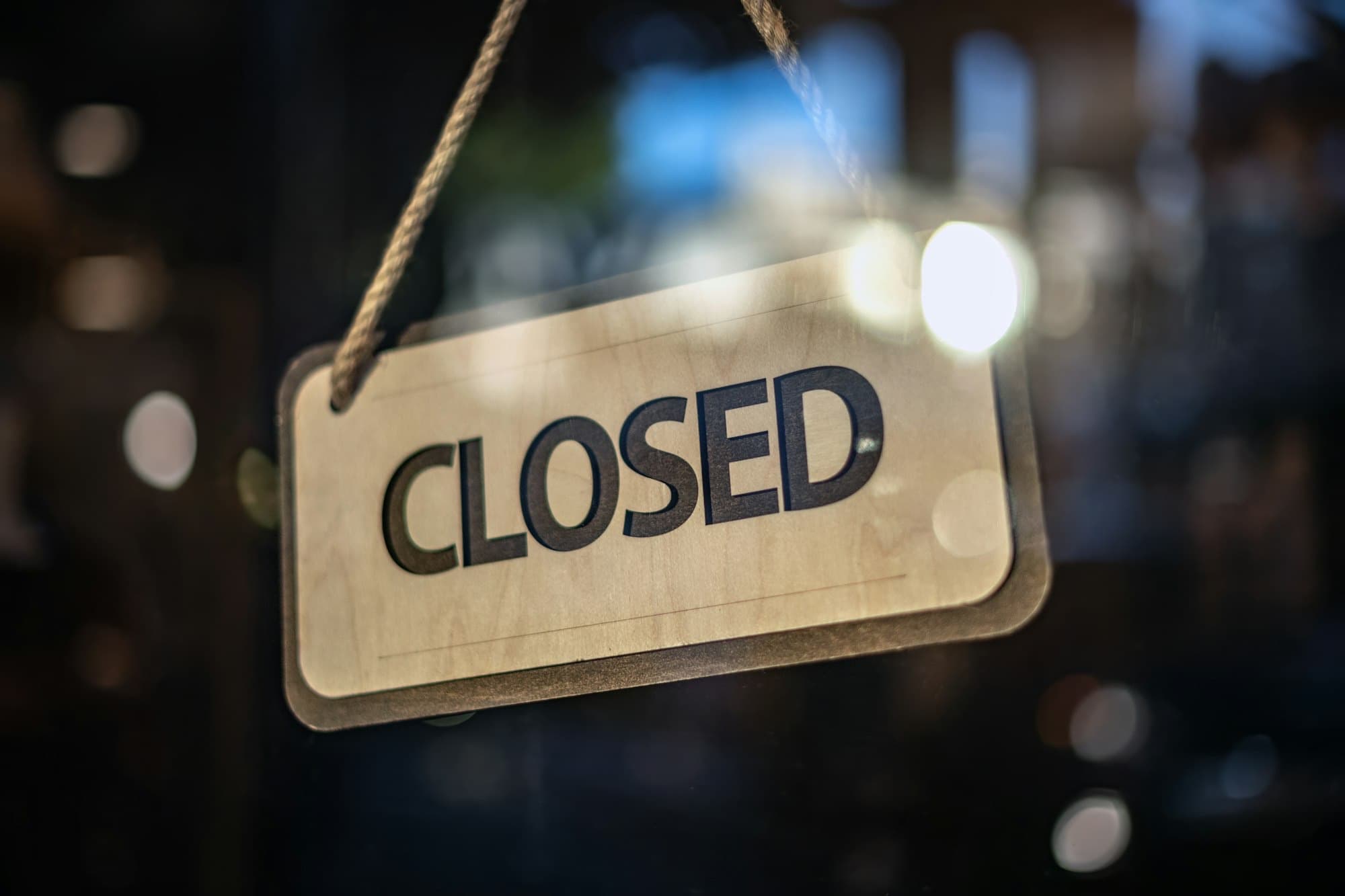 A “Closed” sign hanging on a shop door at night